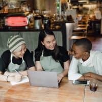 Three cafe employee chatting at a table.